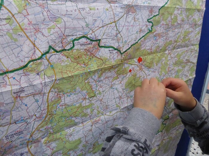 Kinder markieren ihren Heimatort mit roten Punkten auf einer Landkarte 